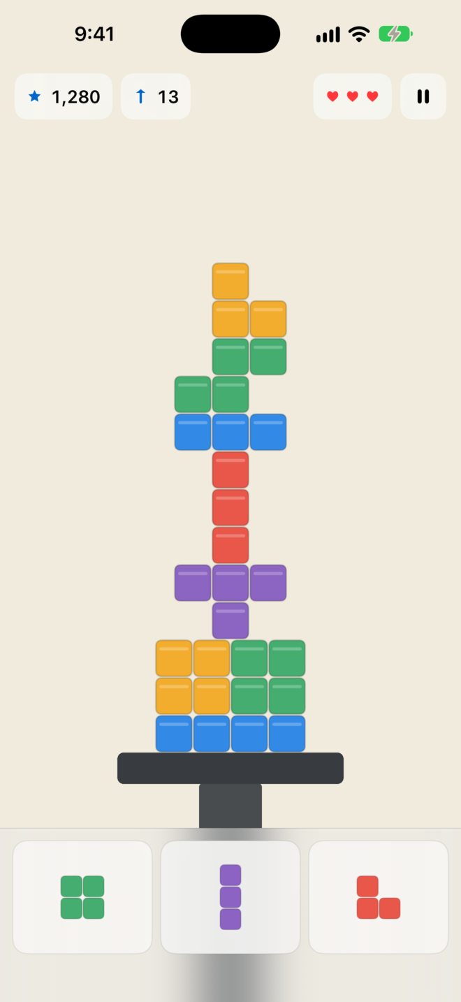 A colorful tower balanced on a platform, with three pieces ready to place